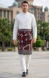 Man wearing a traditional outfit Premium burgundy instant sampin tanjung with elegant traditional Malay design outdoor setting.