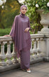 Woman in a Kebaya Moden Dusty Magenta outfit standing on a stone balcony with greenery in the background