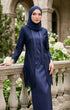 Woman in a baju kebaya Kutu Baru Navy Blue outfit standing in an outdoor setting with floral decorations.