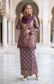 woman wearing Kurung Kedah Lace Songket Magenta full outfit with full songket skirt in an architectural setting.