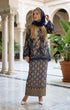 woman posing in Kurung Kedah Lace Songket Blue Black featuring full songket skirt stylingt in an elegant indoor setting with columns and plants.