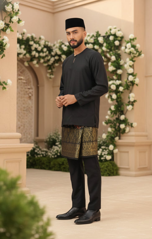 Man in Black Baju Melayu Teluk Belanga traditional attire standing in a decorated outdoor setting with flowers and arches.