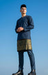 Man wearing a traditional outfit Baju Melayu Teluk Belanga Dark Teal Blue against a clear blue sky.