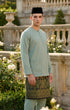 Man wearing a traditional outfit Baju Melayu with a Dusty green top and sampin and songkok in an outdoor setting.