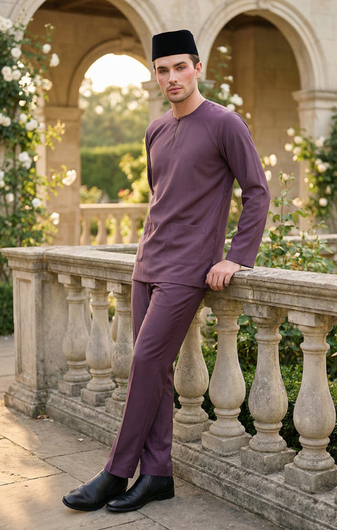 Man in a Baju Melayu Teluk Belanga Dusty Magenta traditional outfit standing on a stone balcony with garden background