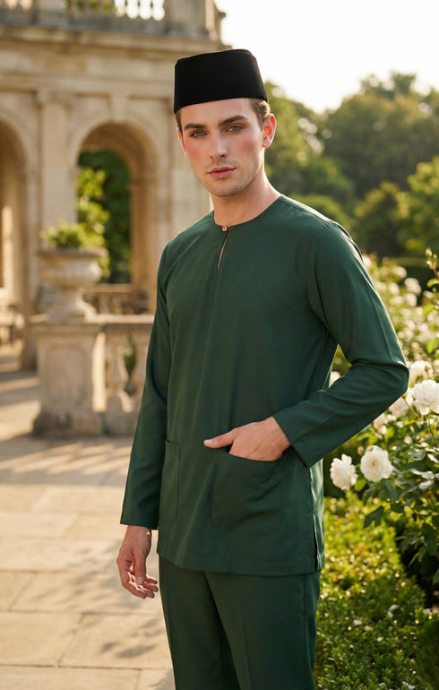 Man wearing a Emerald green traditional baju melayu outfit with a black cap in an outdoor setting.