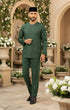 Man in Traditional Baju Melayu Teluk Belanga Emerald Green front view full outfit standing in a decorative outdoor setting with flowers and arches.