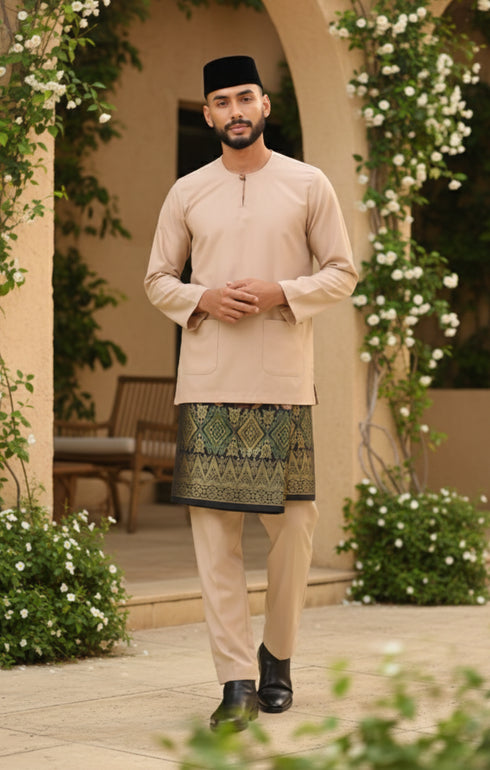 Man in Baju Melayu Teluk Belanga Nude traditional attire standing in a decorative outdoor setting with plants and flowers.