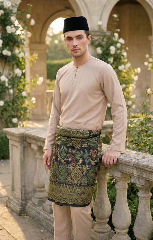 Man wearing a Nude Baju Melayu Teluk Belanga long-sleeve standing on a stone balcony with greenery in the background.
