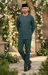Man in Baju Melayu Teluk Belanga outfit standing in a decorative garden with flowers and stone arches.