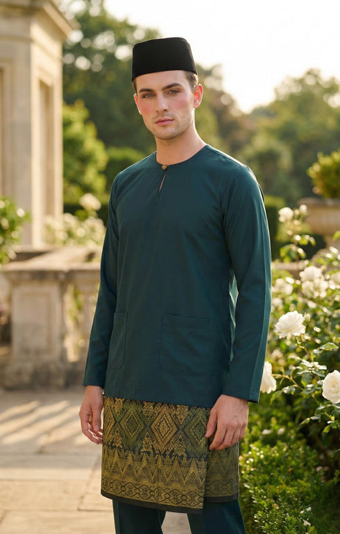 Man wearing a traditional Baju melayu Teluk Belanga outfit with a Teal green top and Tradiotional Sampin in an outdoor setting.