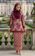 Woman in traditional Kurung Kedah Lace Songket Maroon standing in a garden with classical architecture