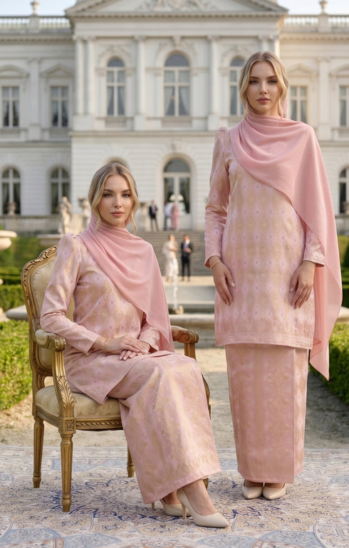 Two women in matching Kurung Moden Dyed Brocade Rose Gold traditional outfits standing in front of a classical building.