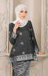 Woman wearing a Kurung Kedah Black Silver showing songket design and fit with a Instant shawl hijab in an elegant interior setting.