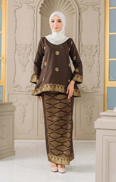 Woman wearing a Kurung Kedah Dark Rich Brown Gold traditional outfit with a matching Instant Shawl in an elegant interior setting.