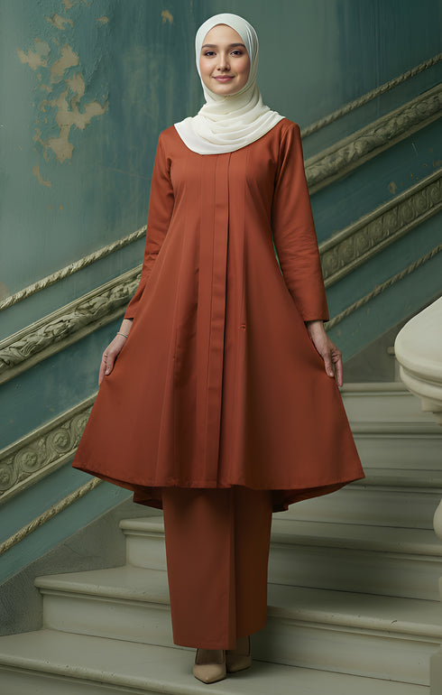 Woman in a Kebarung Klasik Plain Brick Orange front view outfit standing on a staircase with decorative walls.