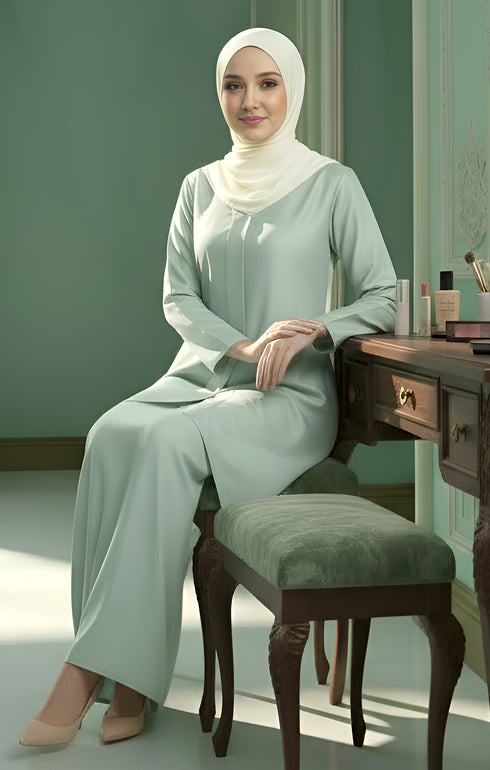 Kebarung Klasik Dusty Green showing smooth cotton sitting on a chair in a room with a desk and mirror.
