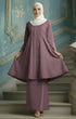 Kebarung Dusty Magenta traditional outfit standing on a staircase with a decorative blue wall in the background.