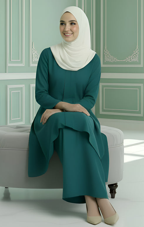 Kebarung Teal Green angled side view showing flowy kebarung klasik fit sitting on chair with a light green wall in the background.