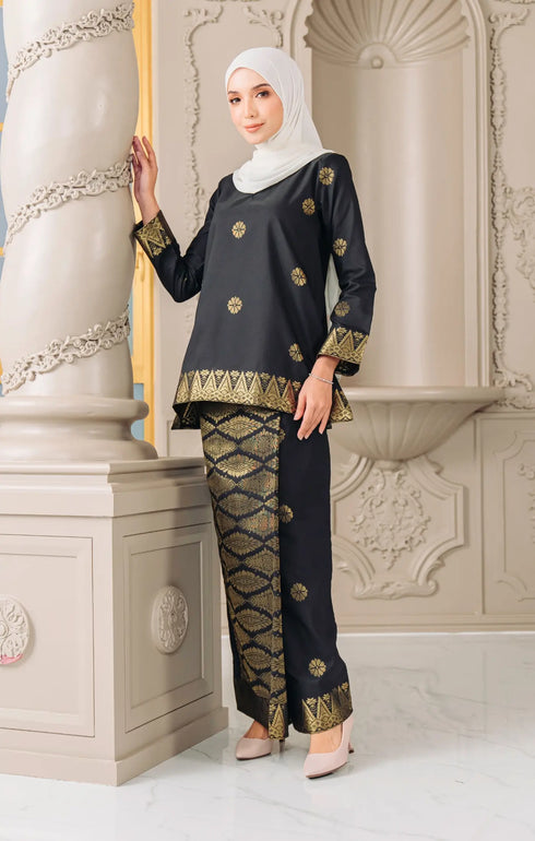 Woman wearing a Kurung Kedah Black Gold traditional outfit with a instant shawl hijab in an elegant interior setting.