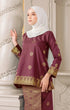 Fabric close up Kurung Kedah Dark Maroon Gold showing songket floral pattern and texture against an ornate white wall.