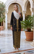 woman wearing Kebaya Kurung Moden Songket Black Gold front view standing in a decorative outdoor setting.