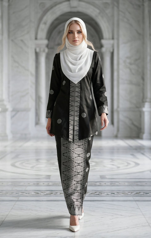 Woman wearing a Kebaya Kurung Moden Songket Black Silver with a shwal hijab in a marble hallway.