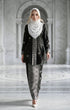 Woman wearing a Kebaya Kurung Moden Songket Black Silver with a shwal hijab in a marble hallway.