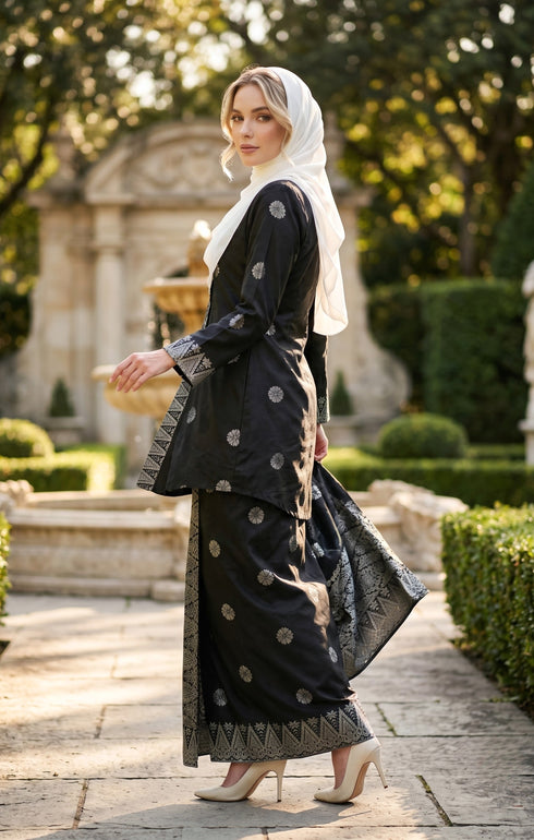 model wearing Kebaya Kurung Moden Songket Black Silver side view showing regular fit silhouette standing in a garden.