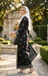 model wearing Kebaya Kurung Moden Songket Black Silver side view showing regular fit silhouette standing in a garden.