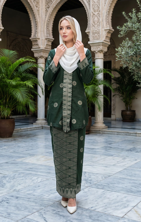 woman wearing Kebaya Kurung Moden Songket Dark Emerald Green Silver front view with V neck design standing in a decorative courtyard with arches and plants.