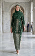 woman wearing Kebaya Kurung Moden Songket Dark Emerald Green Silver full outfit with kepala border kain standing in a marble hallway.