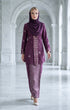 Woman wearing a traditional outfit baju kebaya songket bunga tabur magenta silver with a matching hijab in a marble hallway.