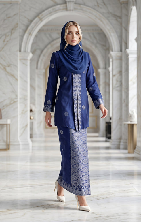 Woman in a Kebaya Kurung Moden Songket Royal Blue Silver traditional outfit standing in a marble hallway