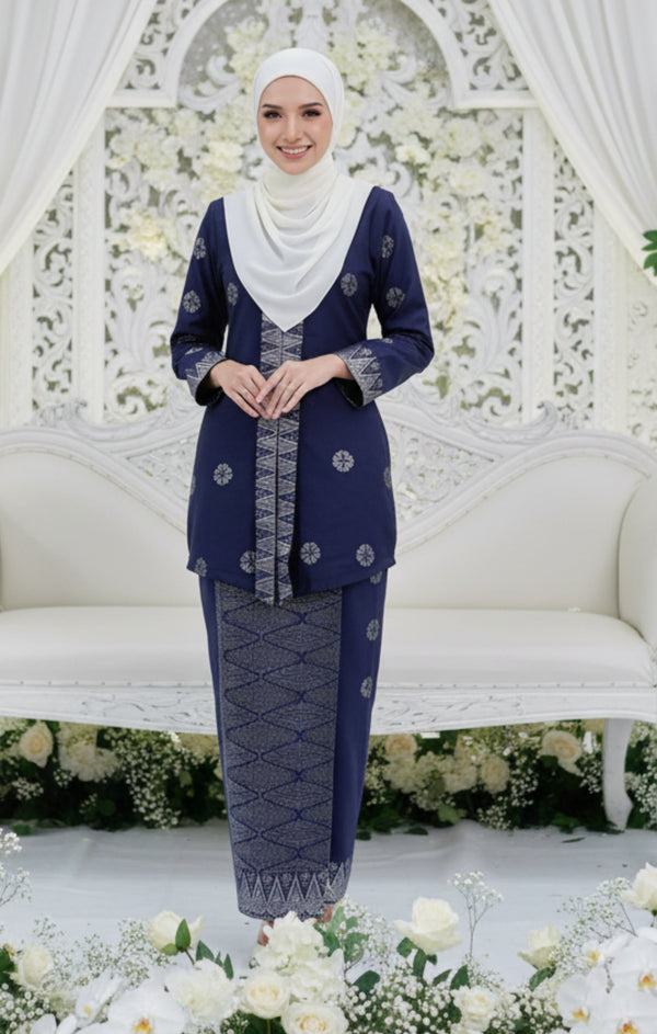 Woman in a traditional navy blue silver outfit with a white floral background