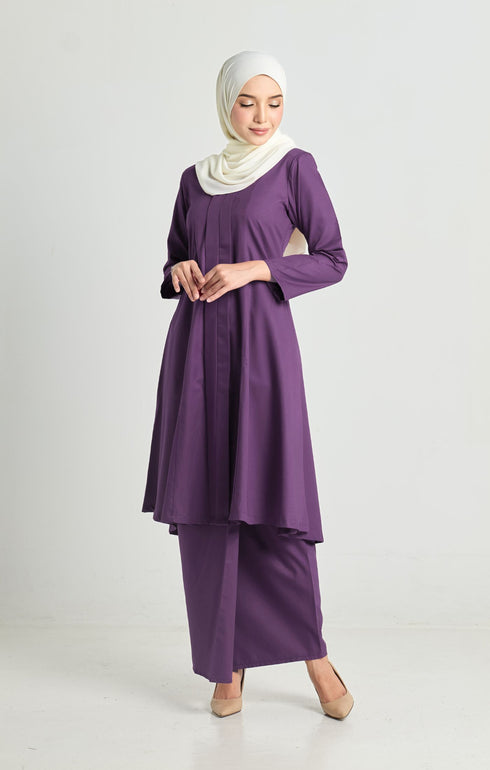 Woman wearing Luna Kebarung Klasik Dark Purple, front view on model. Features V-neck, long straight sleeves, back zip, and plain design in breathable German cotton.