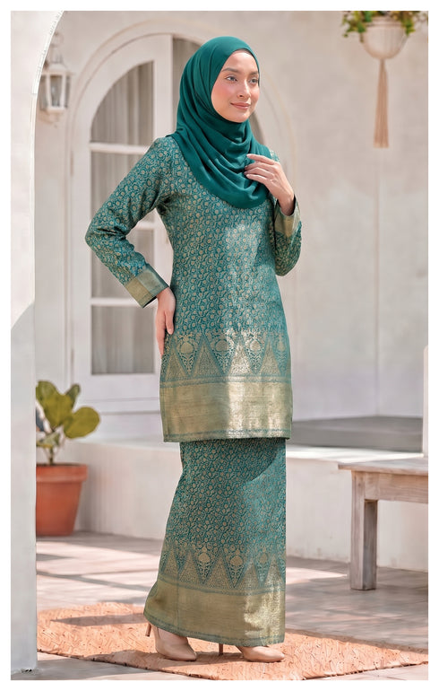 Woman wearing Kurung Moden Teal Green side view showing traditional outfit in an outdoor setting.