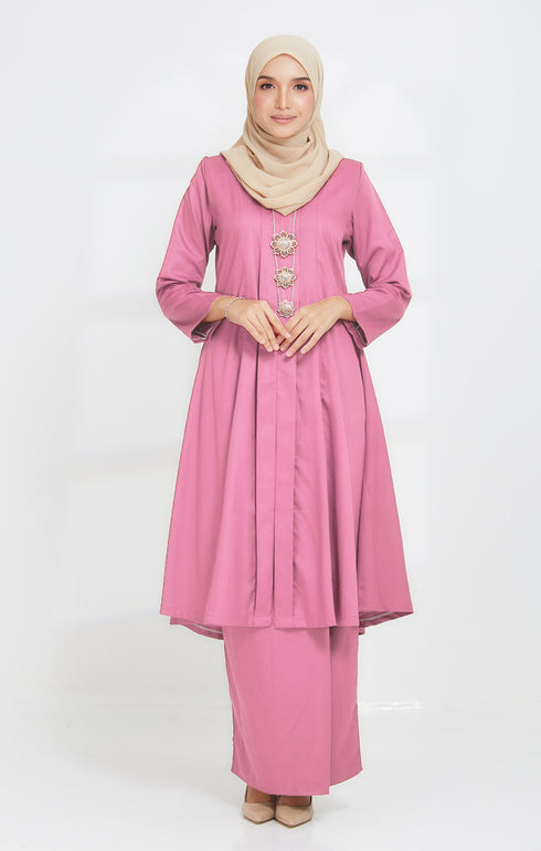 A woman wearing a traditional Kurung Kebaya Pink showing plain cotton design and standard fit with long sleeves and a V-neck collar.